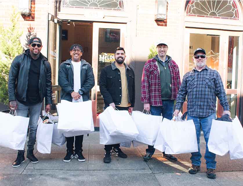 Men holding blankets and coats for homeless outreach